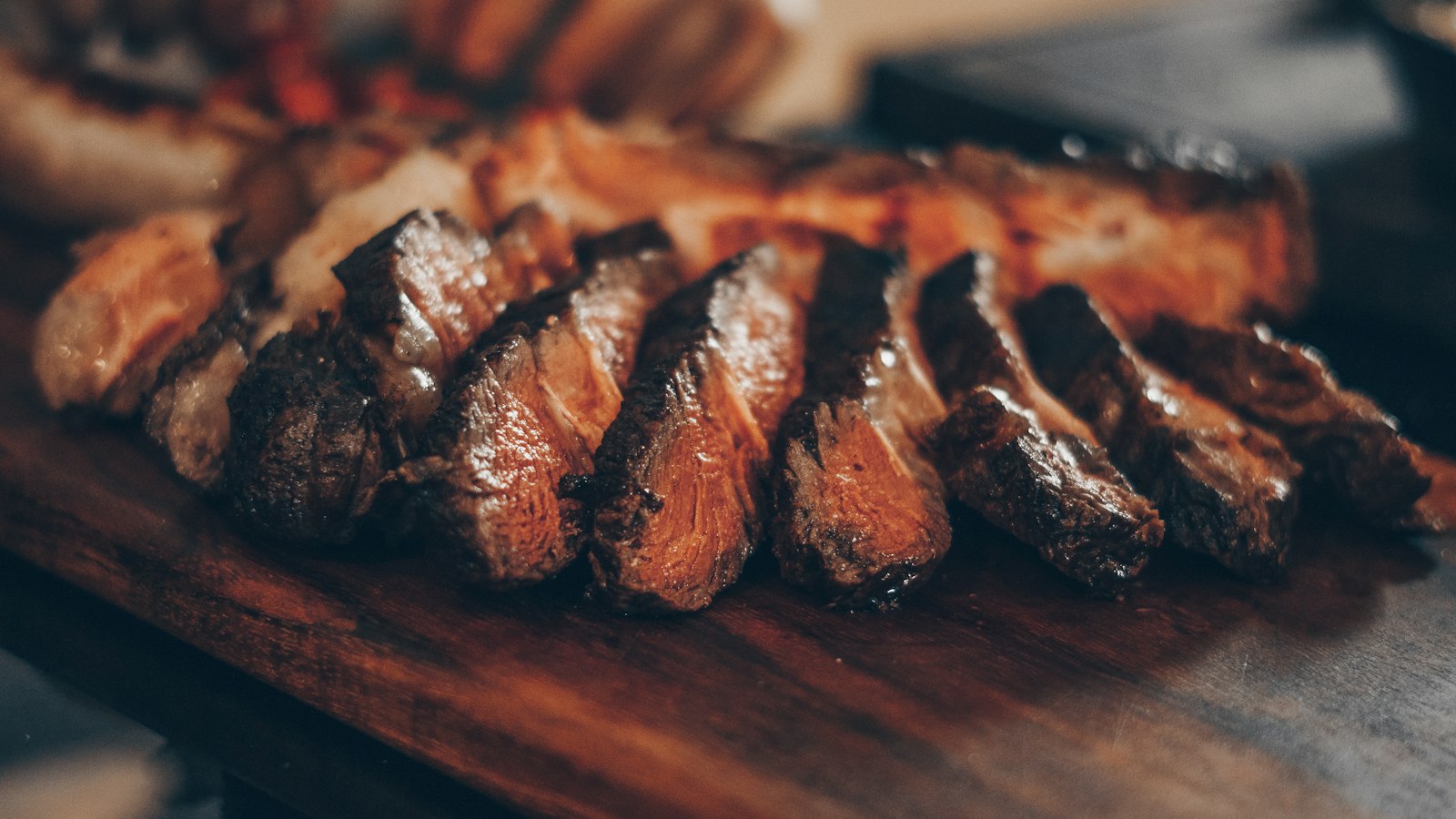 Sliced steak on a dark wooden board