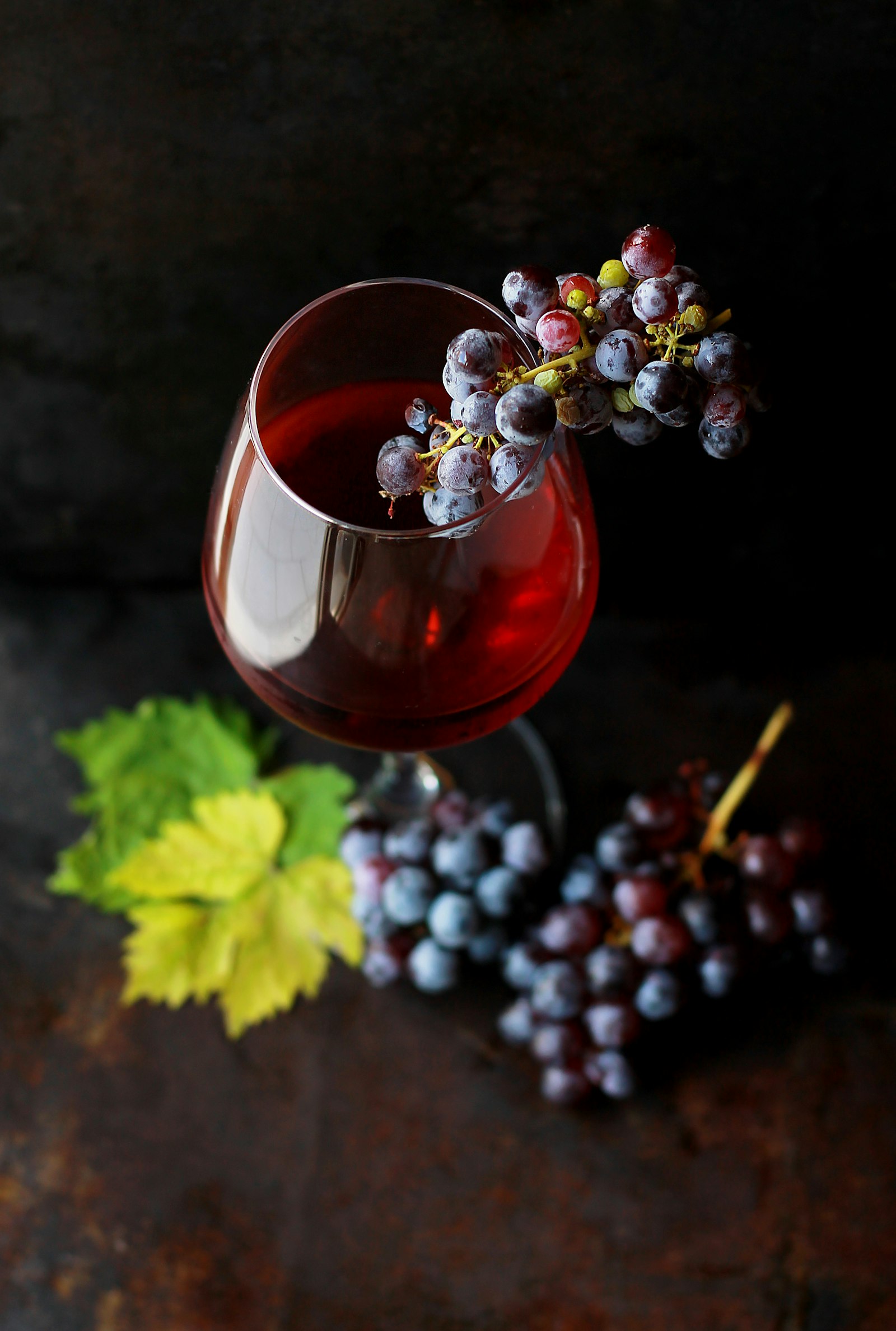 Red wine glass with grapes on a dark surface